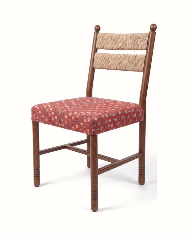 Dining chair angled view, brown wooden legs and arms, beige upholstered back, red patterned seat.