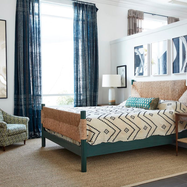 Indigo and ivory striped bedcover draped on bed with matching geometric trim