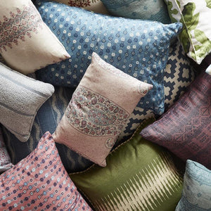 A pile of assorted pillows in different sizes and colors. Each is in a different pattern like stars, paisleys, and stripes.