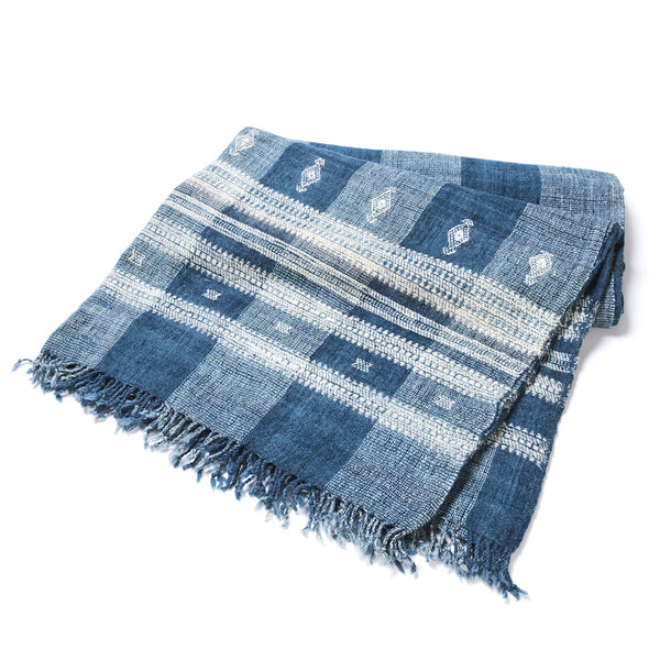 Folded deep indigo and ivory striped bedcover with geometric blocks and stitched bands