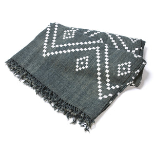 Charcoal bedcover with white zigzag and diamond motifs, fringed border, folded view