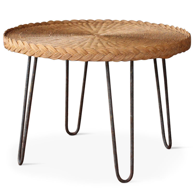 The San Remo End Table, designed by Hollywood at Home founder Peter Dunham, features a circular wicker top with Mid-century styled iron legs in a rustic patina. The table has a braided edge detail with a natural or dark wicker top.